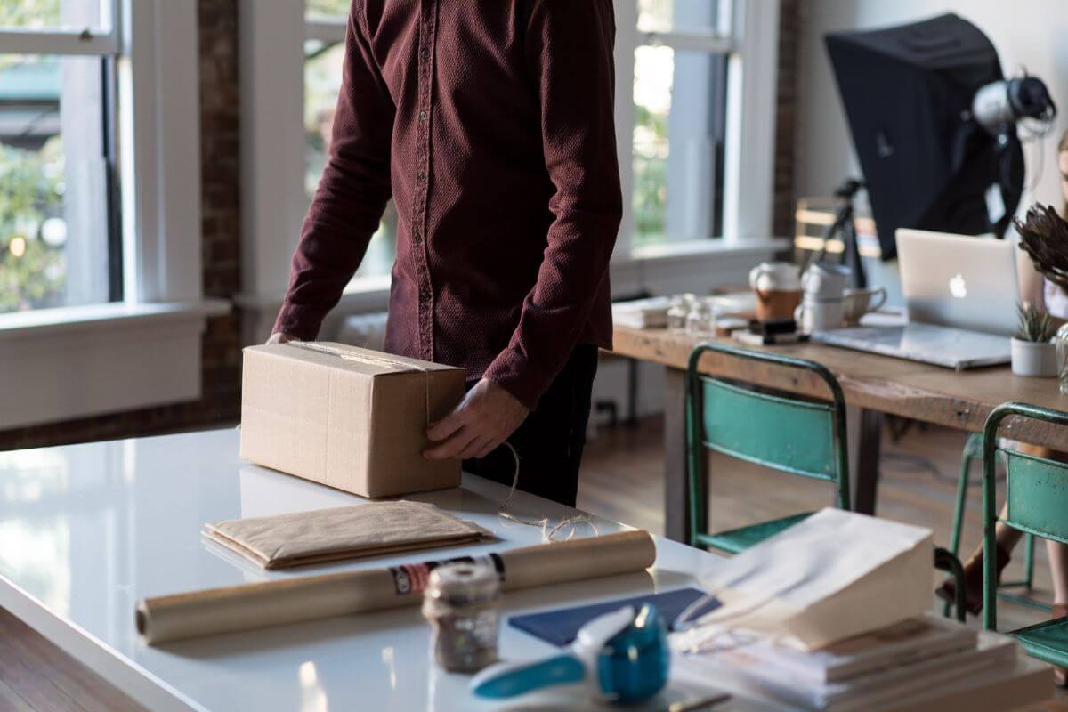 Man holding cardboard box on desk